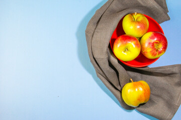 Fresh apples presented on blue background with napkin, creative minimalism concept with copy space