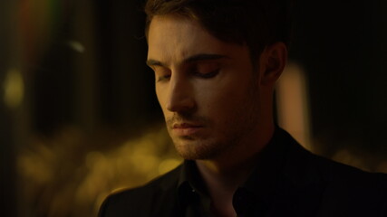 Obraz premium Handsome top manager gazing at camera indoors. Thoughtful man in dark room