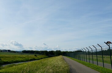 Obraz premium A city hiking trail around the airport Zurich in Switzerland, Europe. The ground is surrounded by a tall fence for safety reasons. There were no flights during corona or cover 19 lockdown. 