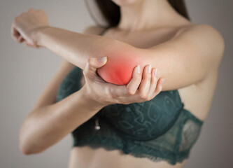 Pain in the elbow in a woman. Highlighted in red. On a gray background. Close up