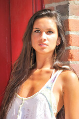 Fototapeta premium Young female model brunette pretty spring top with brick door