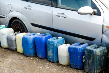 Next to the car are old blue cans with technical liquids. Delivery of gasoline.