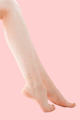 Woman's thin unshaven leg with sparkles on a pink background. Feminism