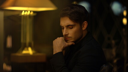 Focused top manager pondering in chair indoors. Serious man touching chin.