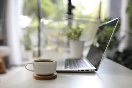 White coffee cup with laptop side view on white desk work from home interior house 