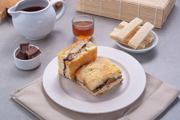 Banana Cake Lekker served on a concrete table with wafers, chocolate bars, honey and tea on the side