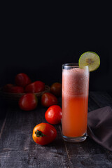 Tomato Juice served on a table with Tomatoes scattered on the side