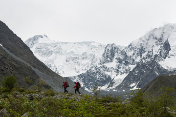 Fototapeta na wymiar two climbers walk along the crest of the mountain against the background of the snow-capped peaks of 