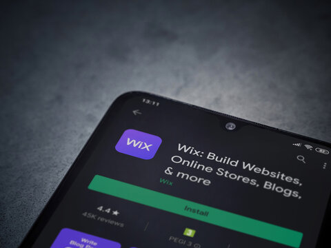 Lod, Israel - July 8, 2020: Wix app play store page on the display of a black mobile smartphone on dark marble stone background. Top view flat lay with copy space.