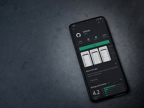 Lod, Israel - July 8, 2020: GitHub app play store page on the display of a black mobile smartphone on dark marble stone background. Top view flat lay with copy space.