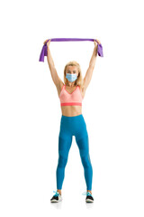 Fototapeta na wymiar Beautiful female fitness coach practicing isolated on white studio background. Caucasian blonde model working in sport outfit and face mask. Professional occupation, active and healthy lifestyle.