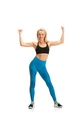 Strong, flexible. Beautiful female fitness coach practicing on white studio background, showing exercises. Caucasian blonde model in sport outfit. Professional occupation, active and healthy lifestyle