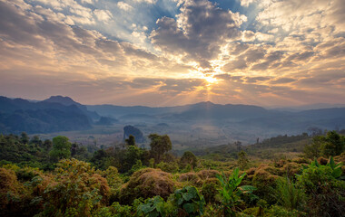 Beautiful sunset sky and mountain range with sky blue and orange light of the sun through the clouds in the sky, Background sky during sunset with fog on mountain, Abundant lush forest-Image