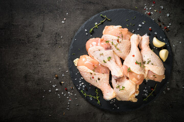 Chicken drumsticks with herbs at black.