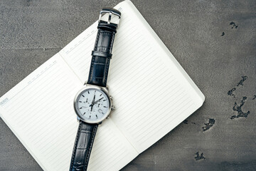 Male watch and notepad on dark grey table