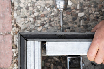 Man assembling composite deck using cordless screwdriver