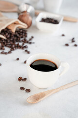 A cup of coffee and coffee beans on white, marble background