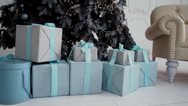 New Year gifts under the Christmas tree in New year photo studio. Gifts are packed in blue boxes. They're under the tree. Camera moved to left. High quality FullHD footage.