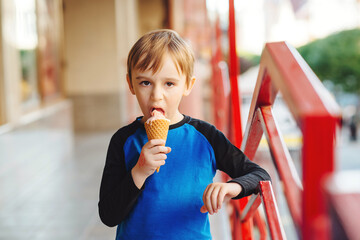 Boy eating ice cream at the city centre. Happy childhood. Cute kid on a summer walk. Tasty fruit...
