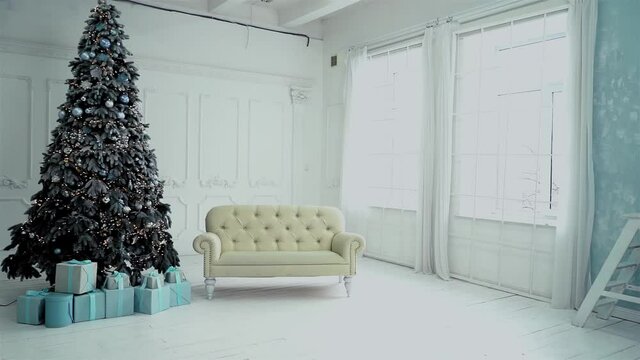Review of the New Year's photo studio. In the frame of a Christmas tree with presents, next to a white sofa. A garland is burning on the tree and balls are hang. High quality FullHD footage. 