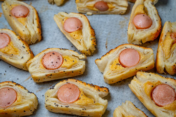 Baking Bun with Sausage and mustard puff pastry rolls. Delicious snacks, tapas, breakfast, appetizers on baking paper. Top view. Close-up