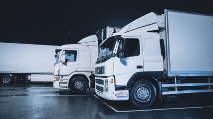 White Semi-Trucks with Cargo Trailer Standing on Overnight Parking Place. Drivers Resting at Night on the Overnight Parking Lot.