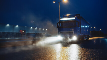 Blue Long Haul Semi-Truck with Cargo Trailer Full of Goods Travels At Night on the Freeway Road,...
