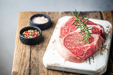 Raw fresh meat Ribeye Steak and seasonings on wooden background, rustic style