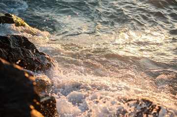 Splashing water, waves on the sea in the rays of the sunset light