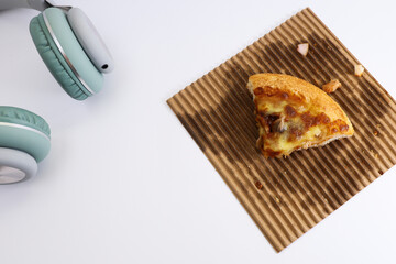 A slice of pizza on the paper liner with headphone on white background