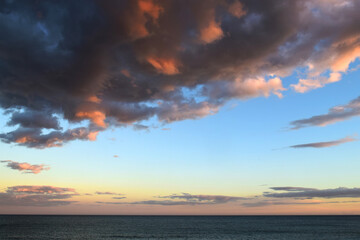 View of the sea with sunset sky and intense stormy clouds