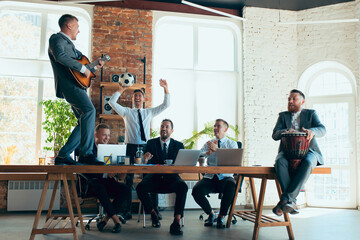 Singing, giving music concert, dancing. Happy carefree colleagues having fun in office while their...