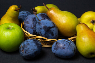 Fruit on a black background. Plums, pears and apples lie side by side. Healthy fruits