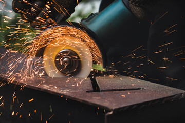 grinding cutting metal sheet with angle grinder machine and sparks, Close up - obrazy, fototapety, plakaty