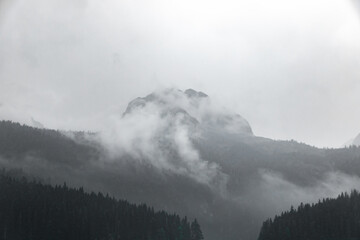 Black and white photo of a high rocky mountain in the clouds