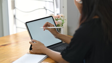 Close up woman holding stylus pen and working with mockup tablet.