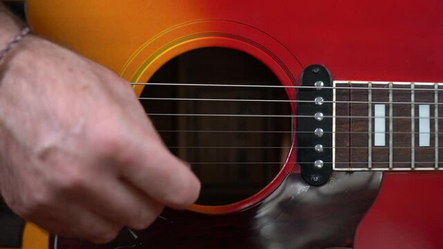 MANI DI UOMO ADULTO SUONANO LA CHITARRA ACUSTICA ARPEGGIANDO ESEGUENDO NOTE MUSICALI