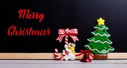 HAPPY CHRISTMAS written in red on a black background near a snowman and a Christmas tree. Christmas concept