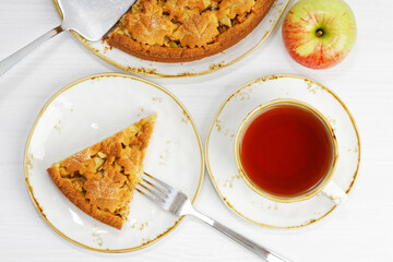 Homemade apple and cinnamon pie and cup of tea on white wooden table. Top view.