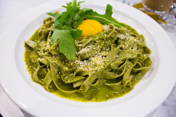 Fettuccine with Creamy Pesto and egg yolk in the middle. White background. 