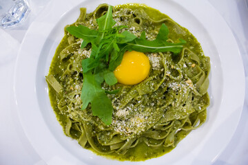Fettuccine with Creamy Pesto and egg yolk in the middle. White background. 