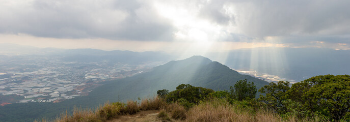 Sun light beams, clouds, mountain and Dalat city in Vietnam, panoramic view - 377376544