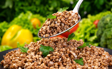 Cooked buckwheat porridge, served with herbs and vegetables on black plate