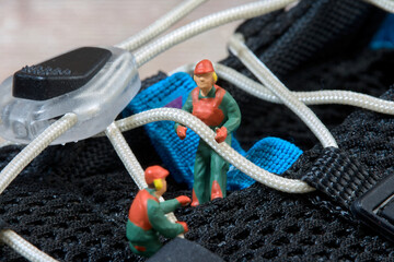 Miniature figures of workers , stretching the laces of a pair of sneakers