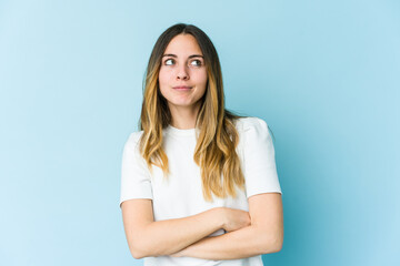 Fototapeta premium Young caucasian woman isolated on blue background dreaming of achieving goals and purposes