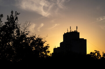 Obraz premium The sun sets behind a building against the sky