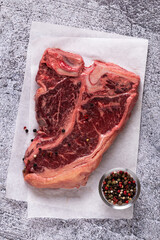 Obraz premium Fresh raw t-bone steak on gray stone background.