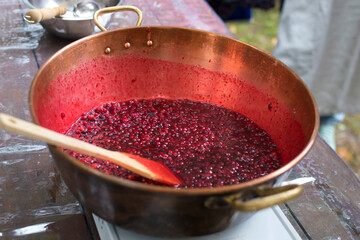 Cooking Finnish lingonberry jam with spices in copper basin on a gas stove
