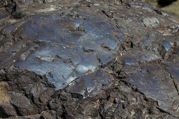 Close-up of a rocky bank of a mountain river with a smooth blue rock. Background for wallpaper, post or illustrations in social networks.