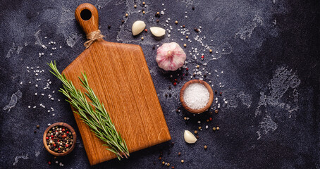 Herbs and condiments on black stone background.